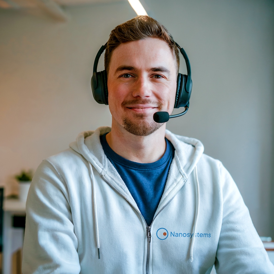 Un técnico de TI con auriculares sonríe, dispuesto a ayudar a los socios a promover y adoptar software para el acceso remoto y la gestión de TI, copias de seguridad y ciberseguridad.